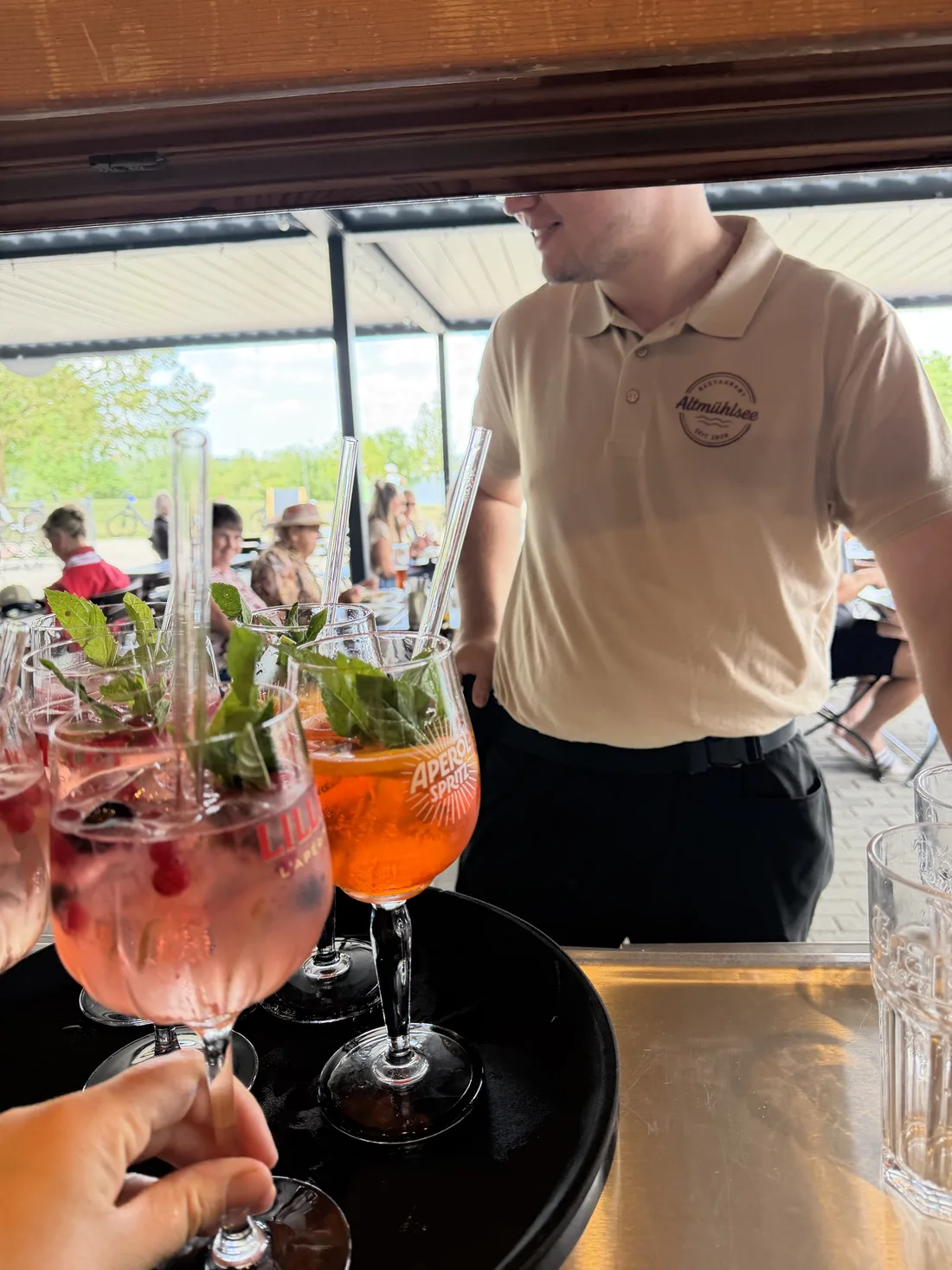 Service bringt frische Aperol- und Lillet-Spritz auf die Terrasse