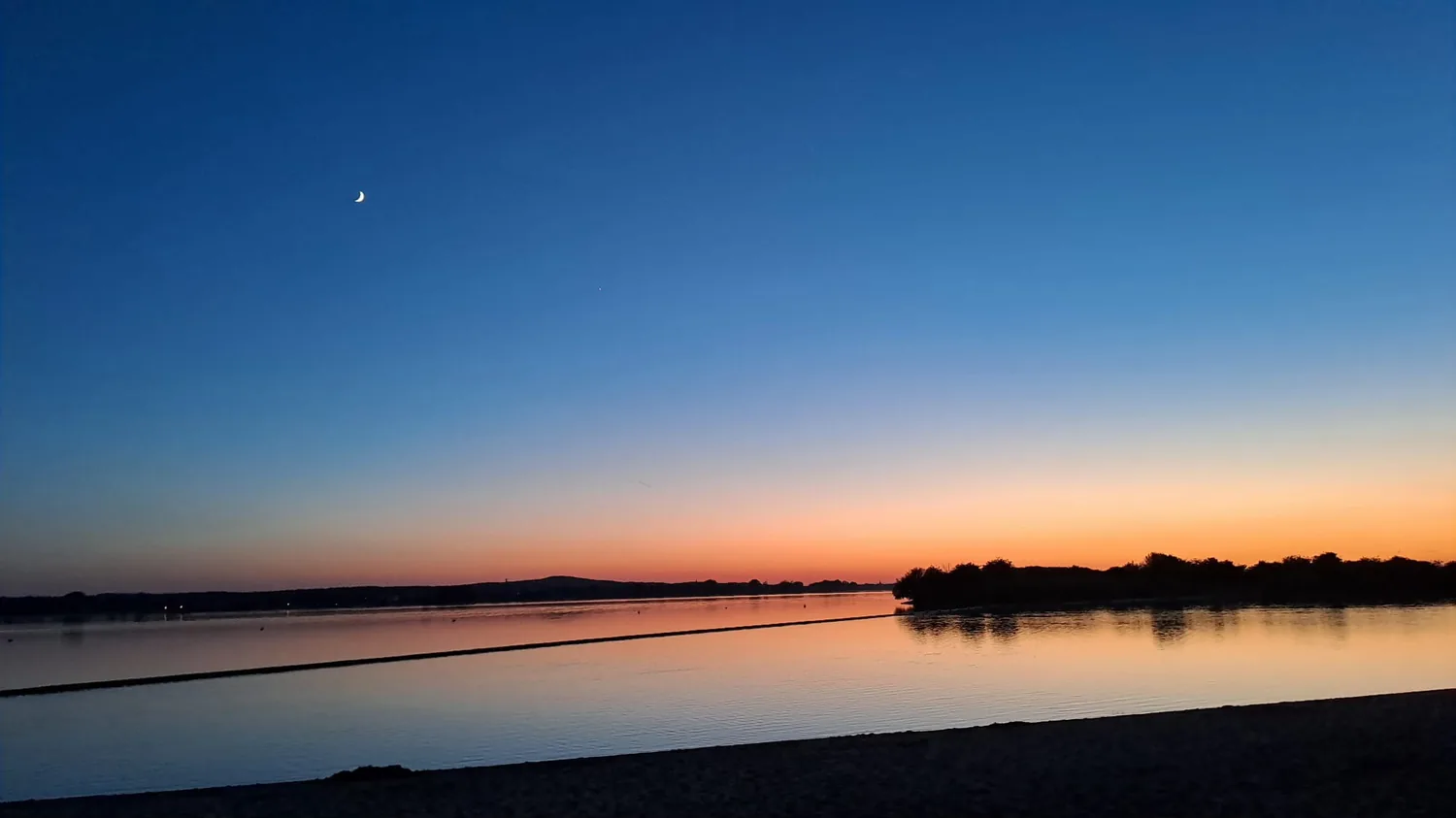 Sonnenuntergang mit Sichelmond über dem Altmühlsee